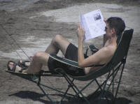 A youth studying a "How To Windsurf" book before taking to the water.  Smart.